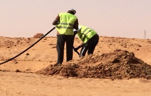 Field team handling cable in desert work area